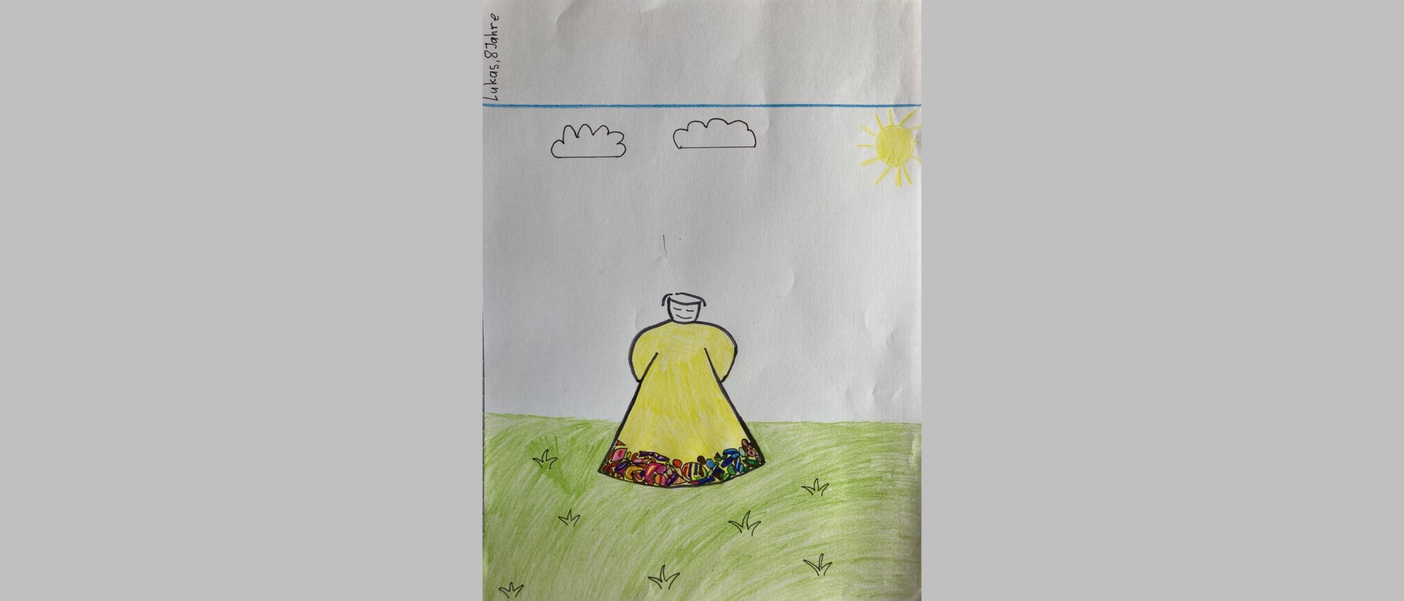 Kinderzeichnung mit Figur in gold-buntem Kleid auf einer Wiese