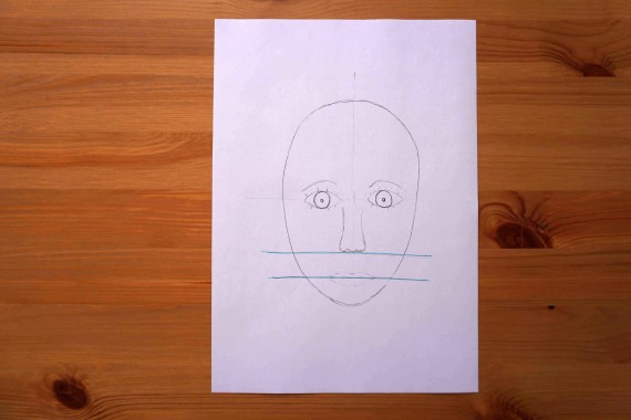 Unterer Teil der Eierform durch zwei Querstriche aufgeteilt, auf oberem gezeichnete Nase, auf unterem Mund